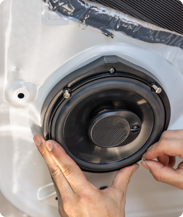 Hands installing car speaker in door.