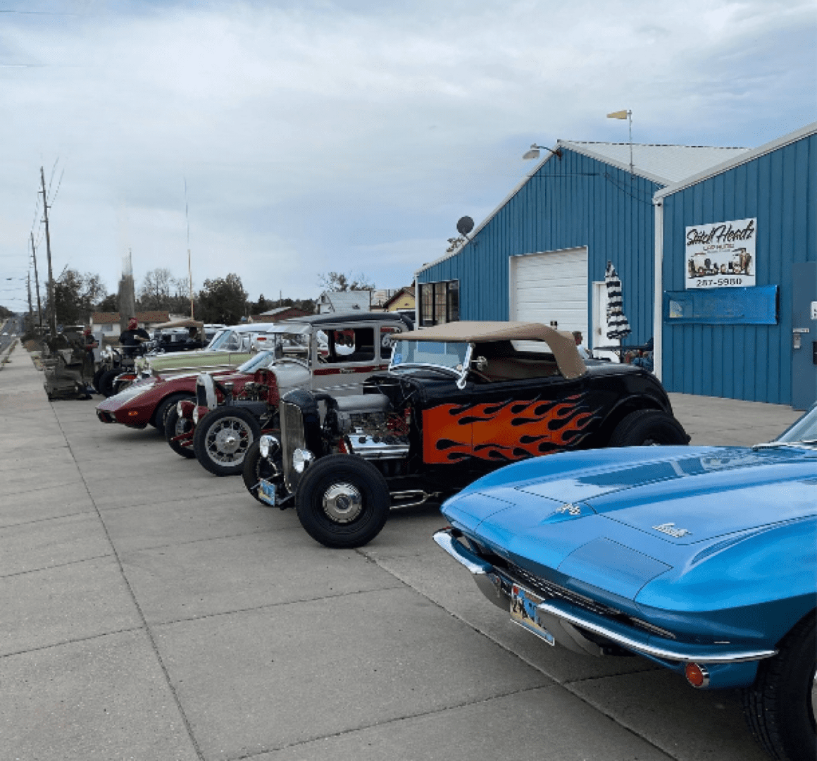 Classic cars parked outside auto shop.